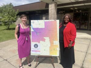 CFL Library Director Jen Graney and NYS Senator Lea Webb standing on either side of a poster of Senator's Webb's District 52, which includes Cortland, Tompkins, and parts of Broome County.